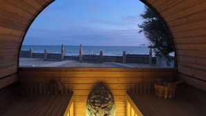 Een houten interieur met een groot, rondbogig raam met uitzicht op een strand.