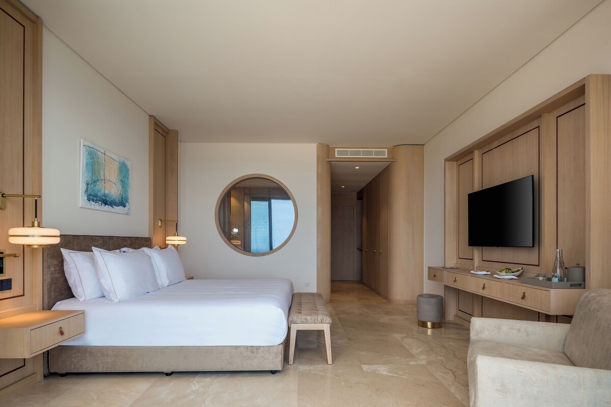 A modern hotel room with a large bed, a television, and a seating area.