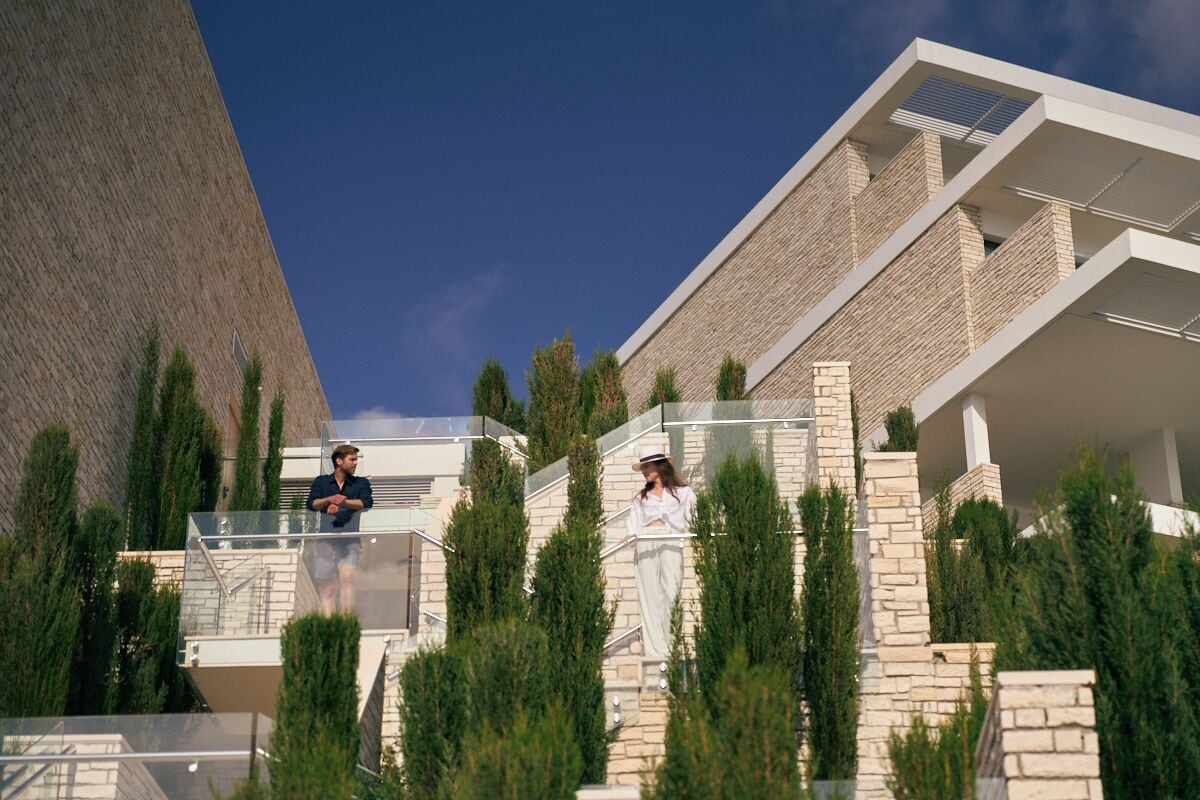 A modern building with a glass balcony and a stone facade.