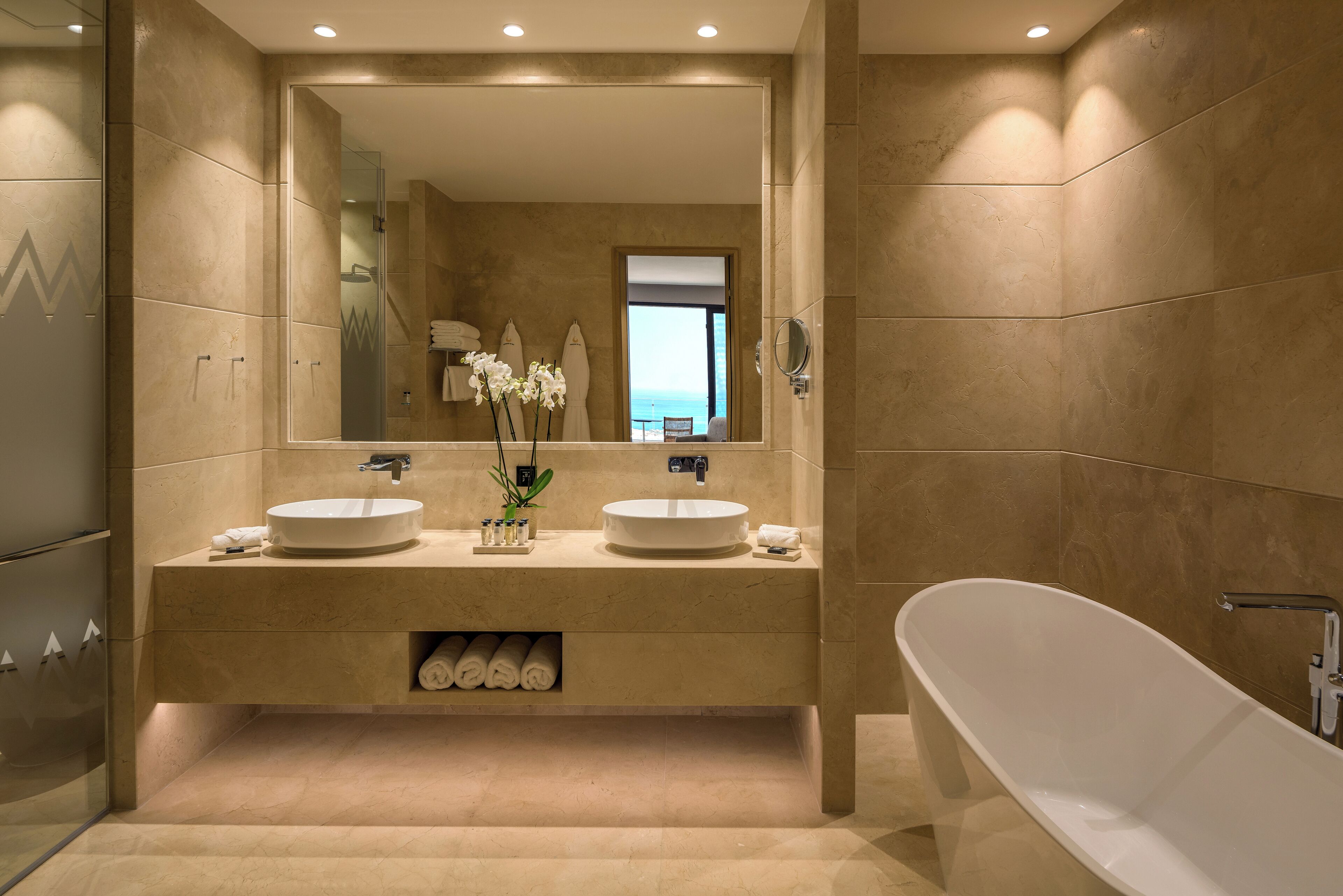 Ein modernes Badezimmer mit zwei Waschbecken, einem großen Spiegel und einer freistehenden Badewanne.