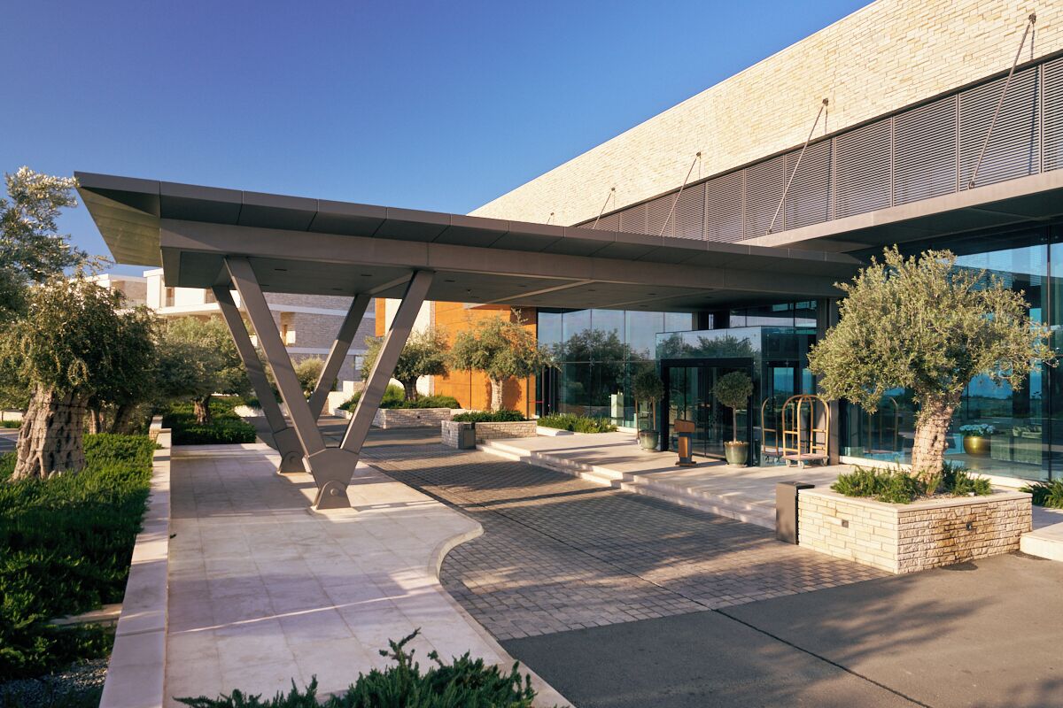 A modern building with a covered entrance, outdoor seating, and landscaped areas.