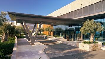 A modern building with a covered entrance, outdoor seating, and landscaped areas.