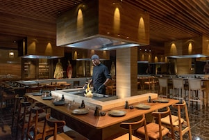 Un restaurante moderno con una isla central, techo de madera y asientos de bar.