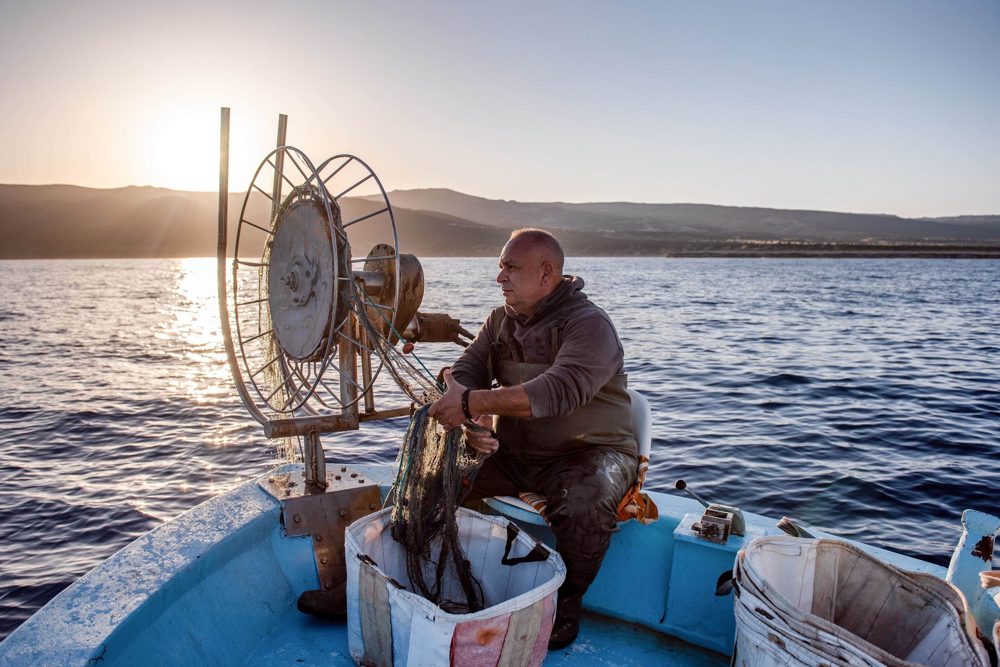 Une personne à bord d’un bateau qui manipule des filets de pêche.