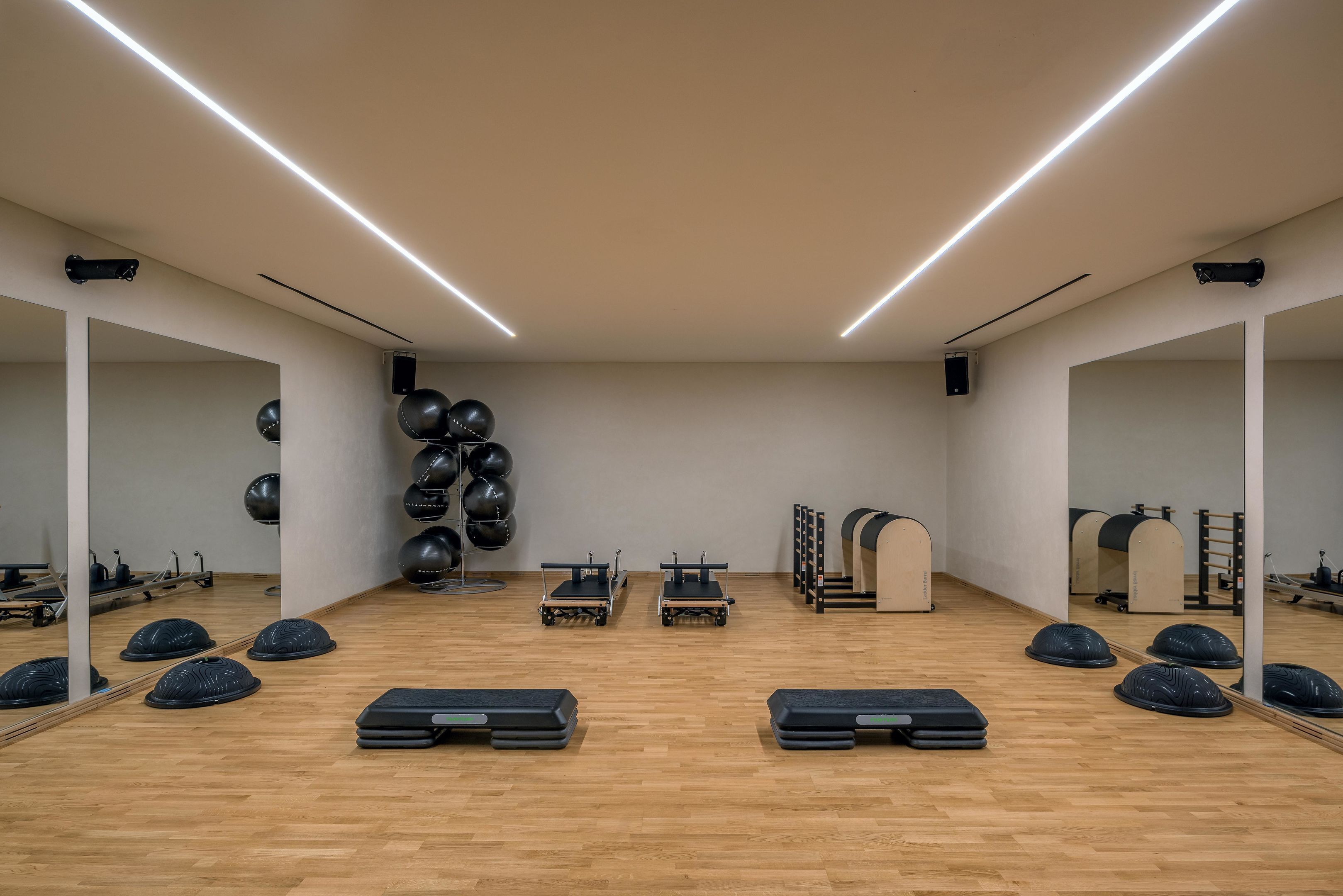Un gimnasio con equipo de ejercicio, espejos y suelo de madera.