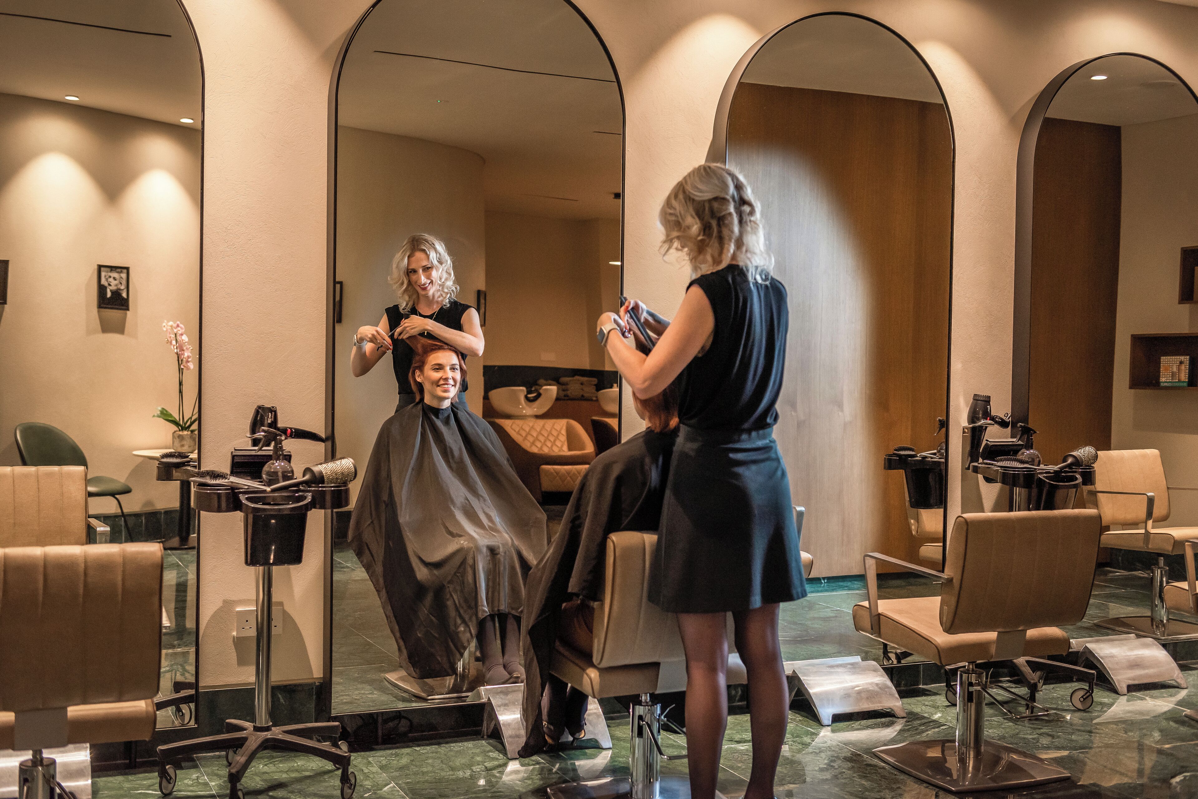 A salon with multiple chairs, mirrors, and a hairdressing station.
