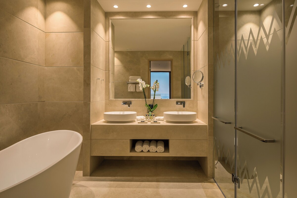 A modern bathroom with two sinks, a large bathtub, and a glass shower enclosure.