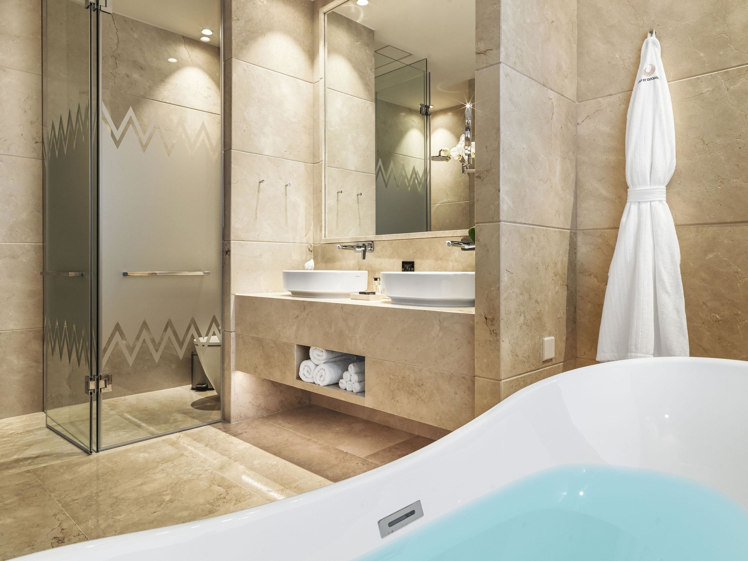 A modern bathroom with a glass shower enclosure, a white bathtub, and a vanity with a sink and mirror.