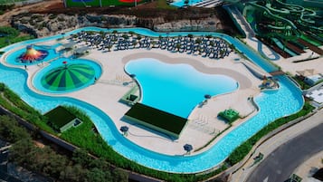 An aerial view of a resort with multiple swimming pools, sun loungers, and a water slide.