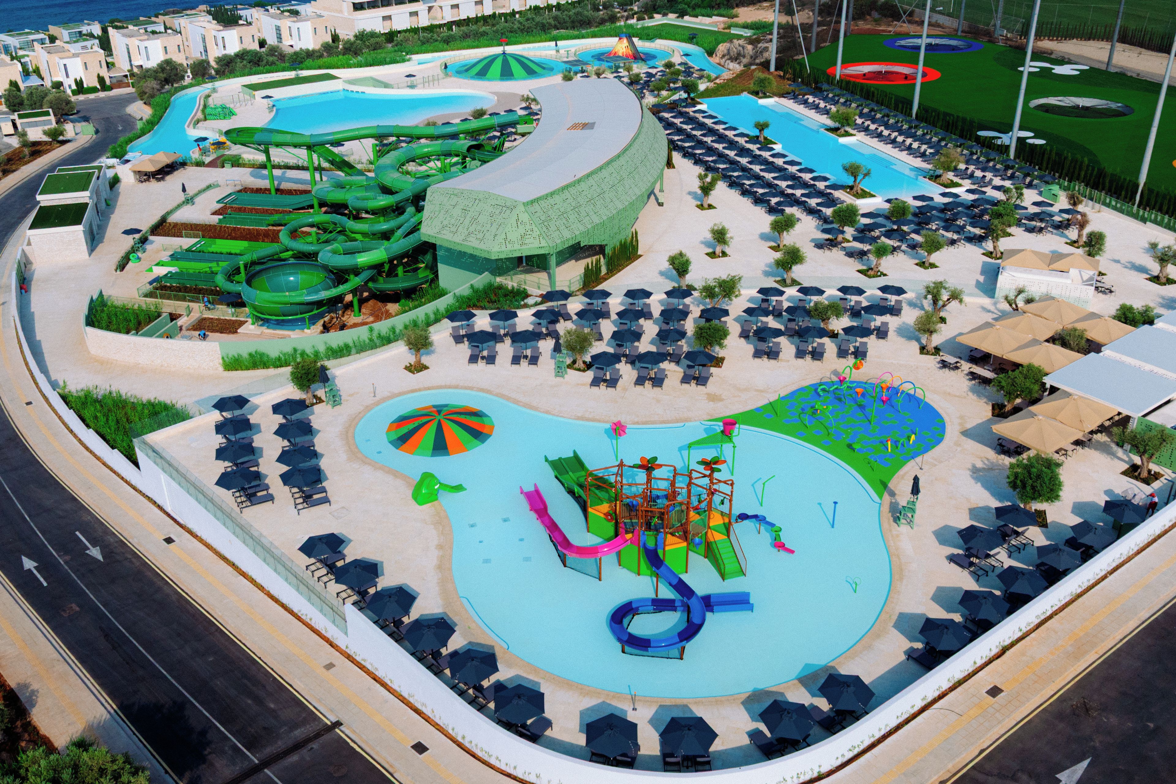 A resort with a large pool area, multiple water slides, and sun loungers.