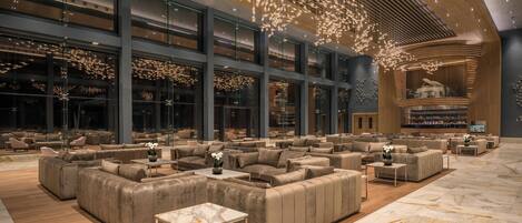 A spacious lobby with multiple seating areas, large windows, and a modern chandelier.