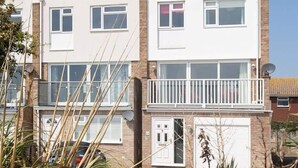 Un immeuble résidentiel de deux étages doté d’un balcon, d’un garage et d’une antenne parabolique.