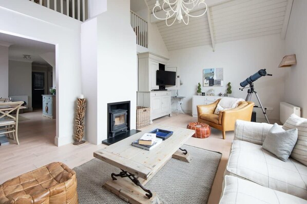 A spacious living area with a fireplace, sofa, and a telescope.