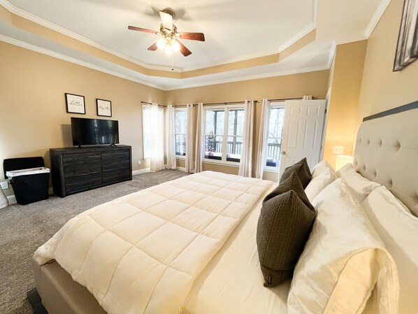 Quarto com uma cama grande, cômoda, televisão e ventilador de teto.