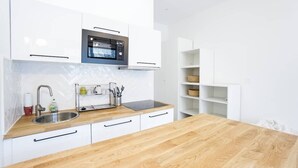 A modern kitchen with white cabinets, a wooden countertop, a built-in oven, and a sink.