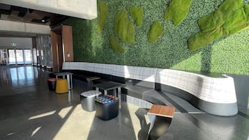 A modern interior with a curved counter, green wall with leaf patterns, and a seating area with a yellow stool.