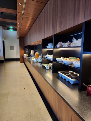 A buffet area with multiple serving stations, each with trays of food, bowls, and plates. - Grand Hôtel TiMES Blainville - Mirabel (Blainville)