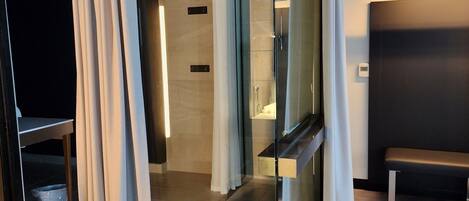 A modern bathroom with a glass shower enclosure, a bench, and a toilet.