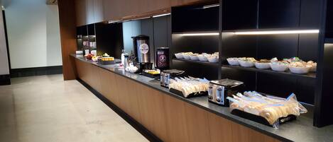 A buffet setup with various food items and a coffee station.