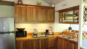 Cocina con armarios de madera, refrigerador, microondas, hervidor, cafetera y pileta.
