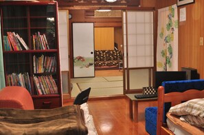 A traditional Japanese room with tatami flooring, a bookshelf, a futon bed, and a shoji screen. - Yukuiru (Miyakojima)