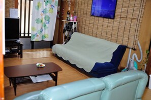 A living room with a sofa, a table, a television, and a fire extinguisher. - Yukuiru (Miyakojima)