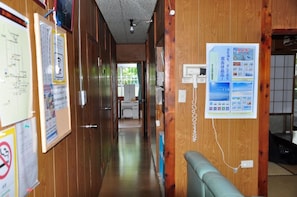 A corridor with wooden walls, a bulletin board with notices, and a seating area with a cushion.