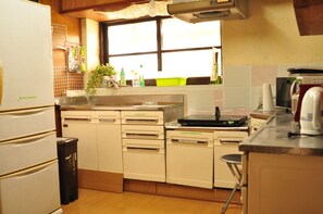 A compact kitchen with white cabinets, a sink, a stove, and a microwave.