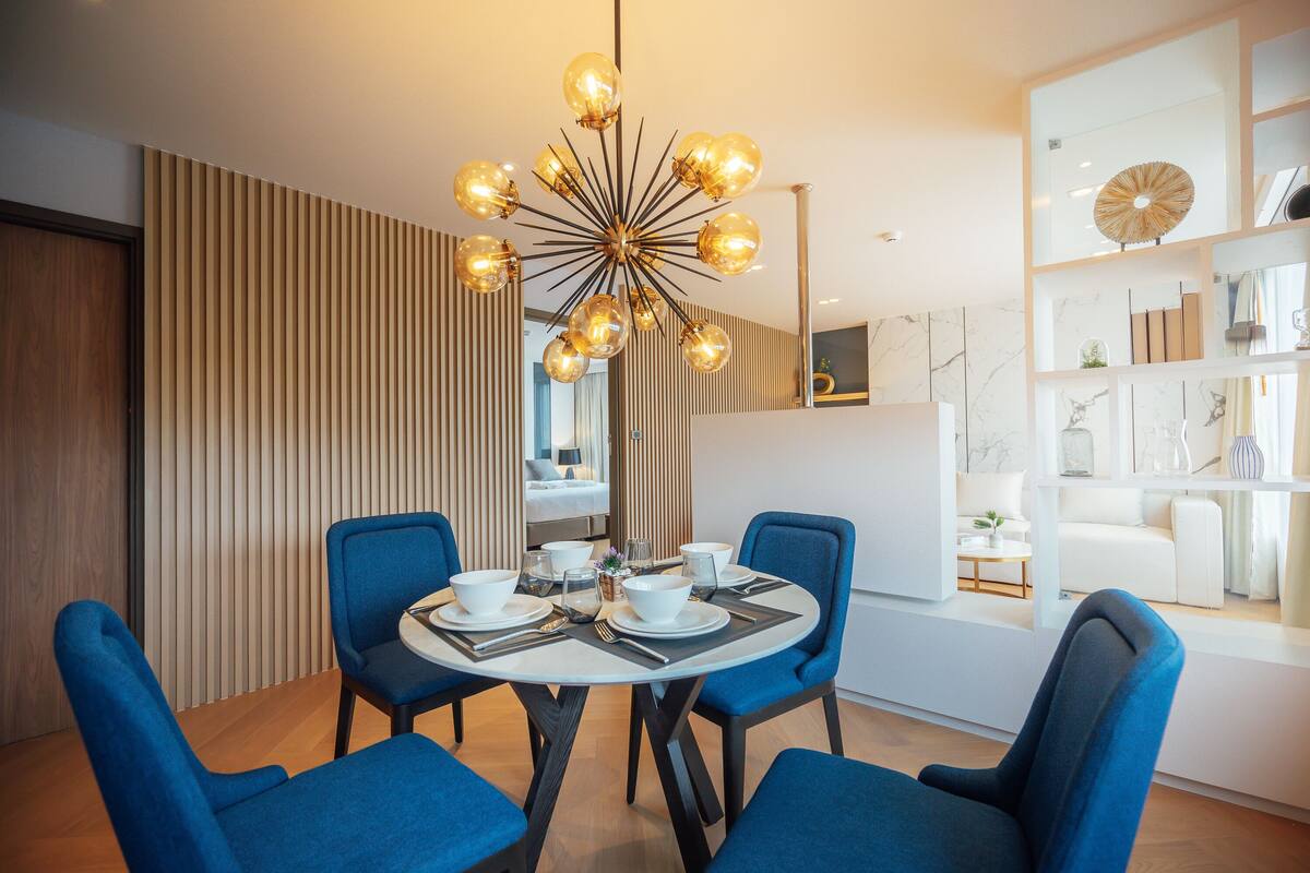 Un espace de salle à manger moderne avec une table ronde, des chaises bleues et un lustre original.