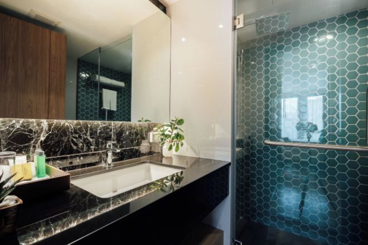 Un bany modern amb un mirall gran, una superfície de marbre i una cabina de dutxa de vidre.