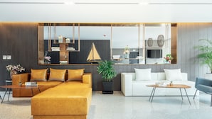 Ein modernes Wohnzimmer mit einem gelben Sofa, einem weißen Sofa und einem blauen Sessel. Es gibt einen Couchtisch, einen Beistelltisch und einen Topfpflanzen.