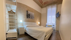 Ein Hotelzimmer mit Bett, Nachttischen, einem Schrank und einem Fernseher an der Wand.