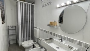 Ein modernes Badezimmer mit einem großen Spiegel, zwei Waschbecken, einer Toilette und einer Dusche.