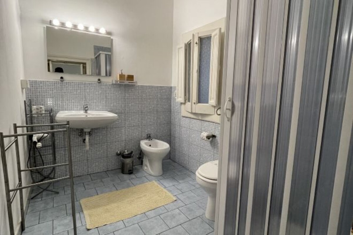 A bathroom with a sink, bidet, toilet, and a mirror with lights.