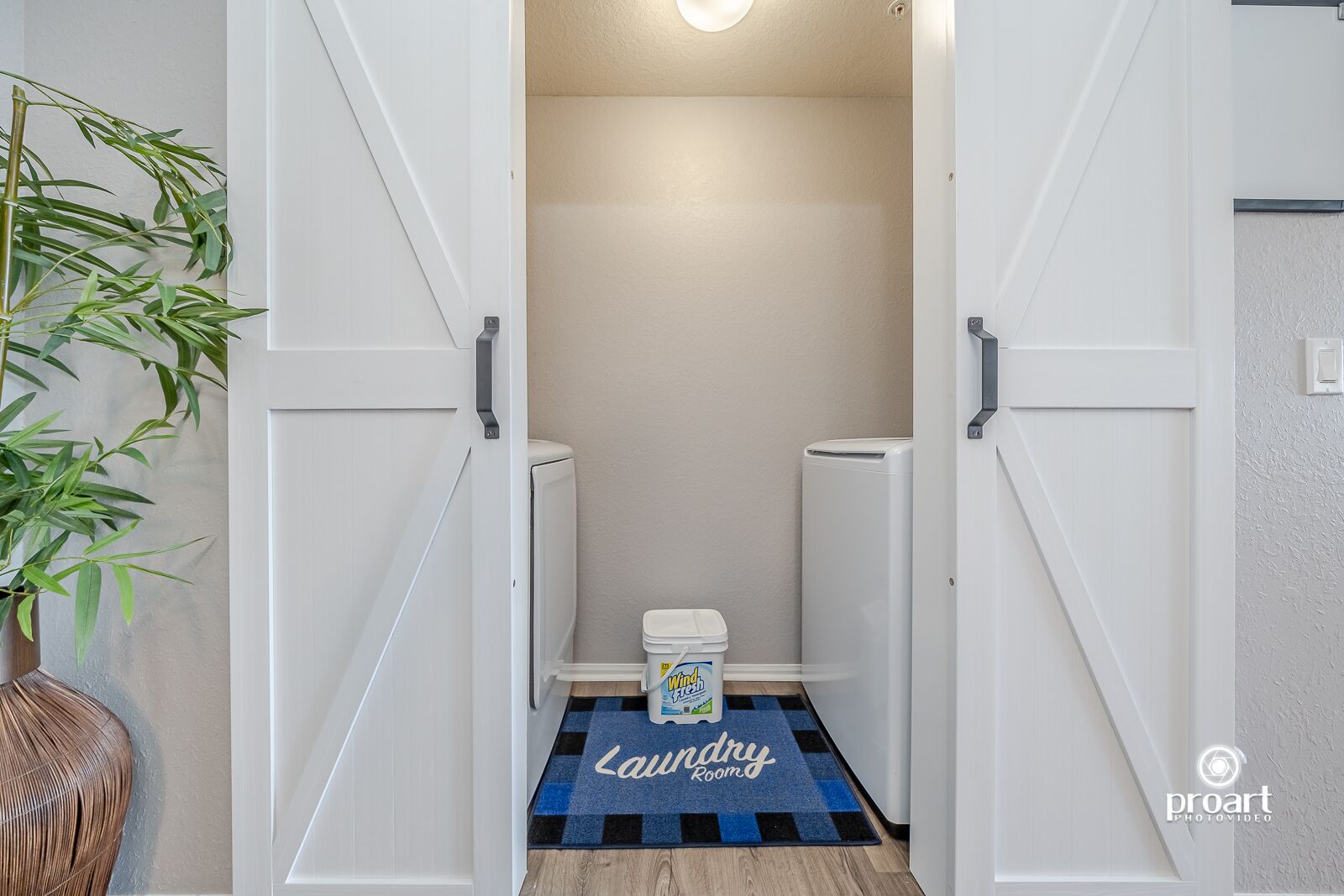 A laundry room with a checkered floor mat labeled "Laundry Room," a white washing machine, and a white dryer.