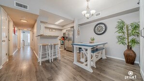 Een moderne keuken met een eethoek, houten vloeren en een grote klok aan de muur.