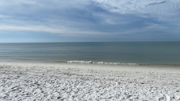 A beach with a clear sky and calm sea. - Pickleball, beach, pool, tennis, nextdoor to Publix, Junkanoo's and Fresh Catch. (Fort Myers Beach)