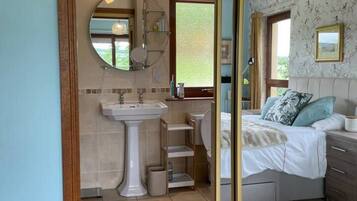 A bathroom with a pedestal sink, a mirror, and a window.