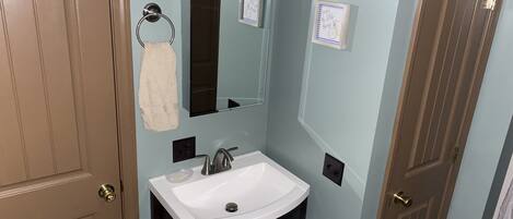 A bathroom with a white sink, a mirror, and a towel ring.