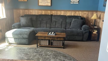 A living room with a sectional sofa, a coffee table, and a fireplace.