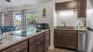Una cucina moderna con mobili in legno scuro, un piano di lavoro in granito, un forno a microonde integrato e un frigorifero in acciaio inossidabile.