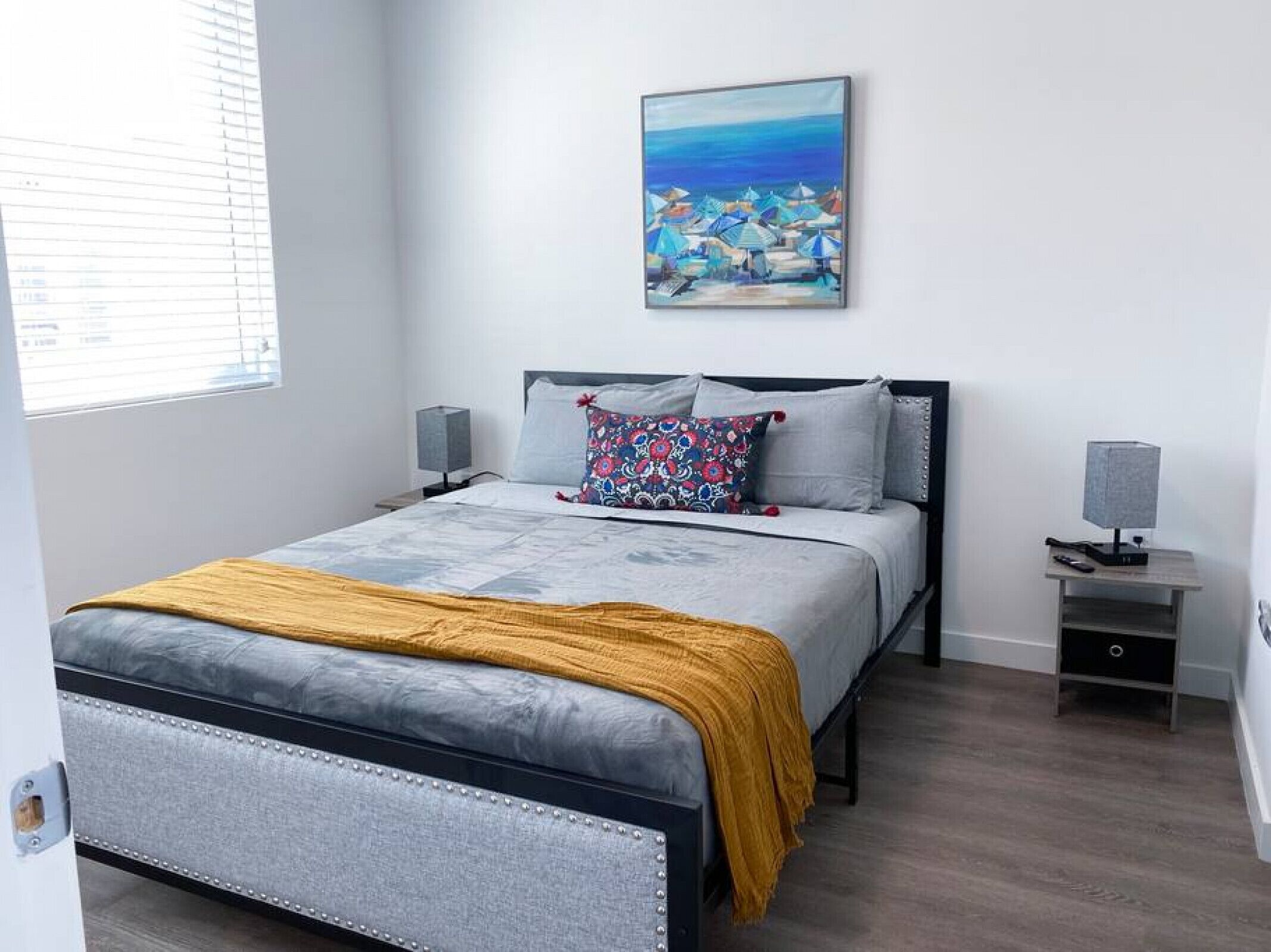 Une chambre à coucher moderne avec un lit, des tables de chevet, un tableau et une fenêtre.