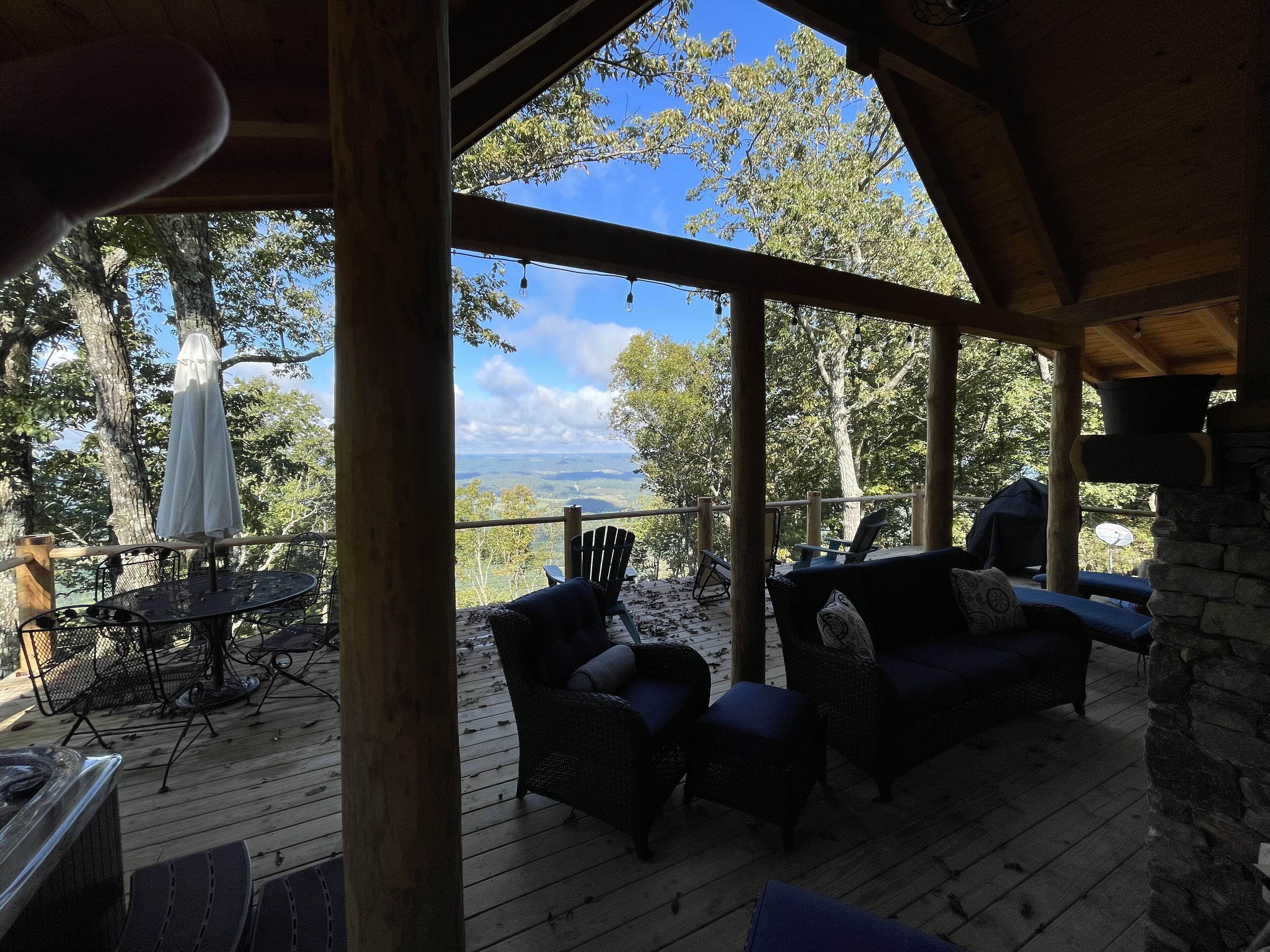 A covered outdoor seating area with wicker furniture and a view of the landscape.