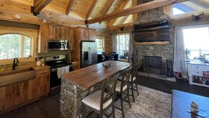 Una cocina amplia con vigas de madera, una chimenea de piedra y una isla grande con taburetes de bar.