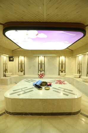 Relax in a serene spa area with a curved marble bench, illuminated ceiling, and sleek sinks.