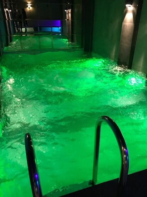 Swimmers can enjoy a refreshing dip in this indoor pool, surrounded by walls and illuminated by mounted lights.