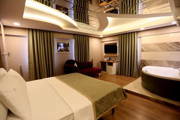 Relax in a spacious room with a large bed, separate seating area, and a bathtub.