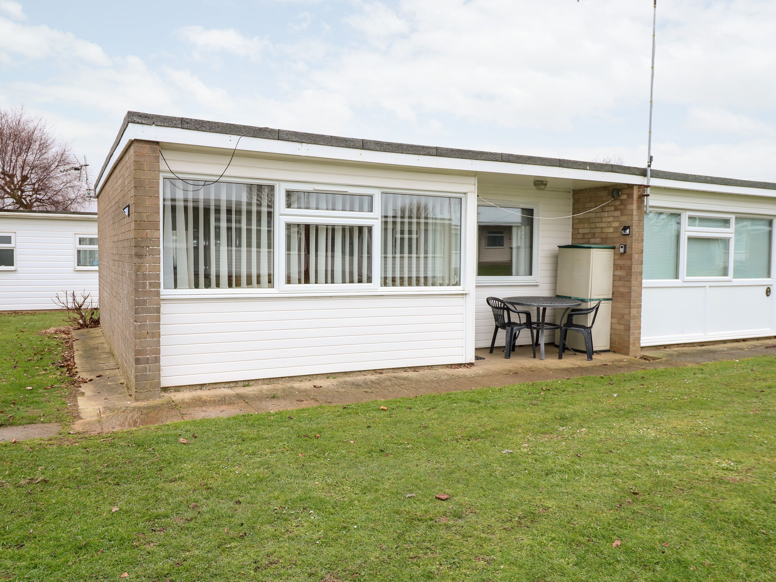A single-story mobile home with a patio area, a small table, and chairs.