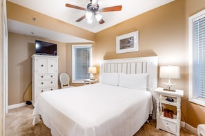 Relax in comfort with a spacious bed, ceiling fan, and large window with blinds.