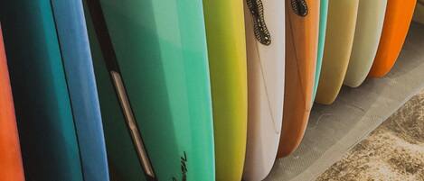 A row of surfboards with various colors and a textured floor.